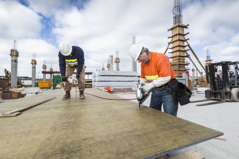 Caucasian workers drilling plant at construction site