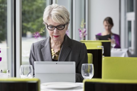 Caucasian businesswoman using tablet computer in restaurant
