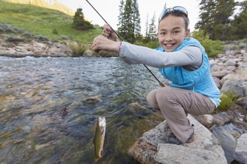 Mixed race girl fishing in river