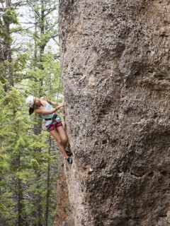 Mixed race girl climbing steep cliff