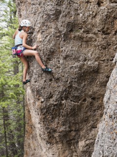Mixed race girl climbing steep cliff