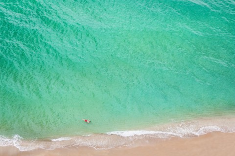 Aerial view of Caucasian man swimming in ocean on beach