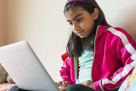 Indian girl using laptop on bed