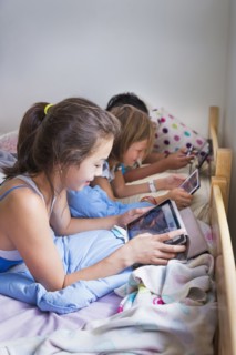Girls using digital tablets on bed