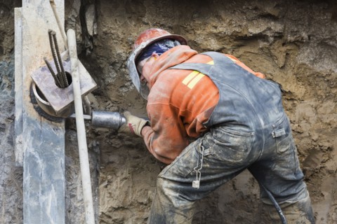 Caucasian worker drilling at construction site