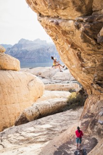 Mother belaying daughter rock climbing on cliff