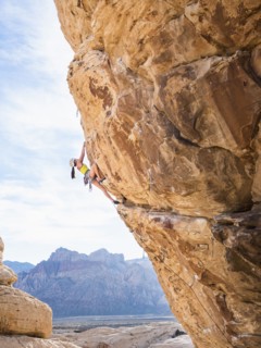 Mixed race girl rock climbing on cliff