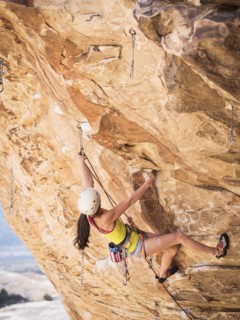 Mixed race girl rock climbing on cliff