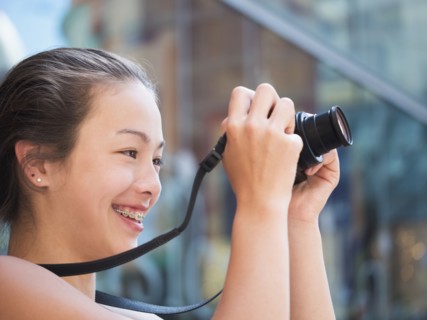 Mixed Race girl photographing outdoors with digital camera
