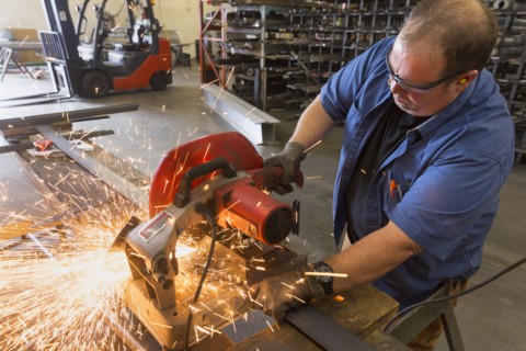 Caucasian worker cutting metal in factory