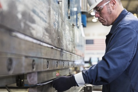 Hispanic worker fabricating metal in factory