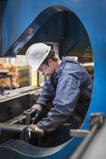 Caucasian worker fabricating metal in factory