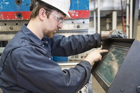 Caucasian worker using control panel in factory