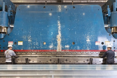 Workers fabricating metal in factory