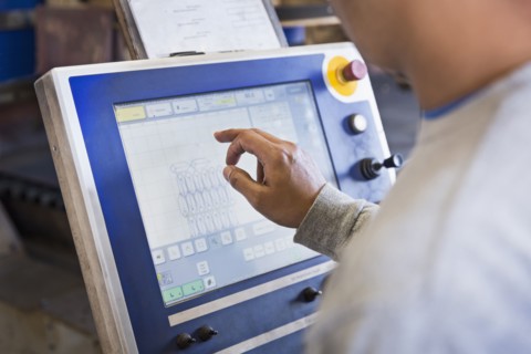 Asian worker using control panel in factory
