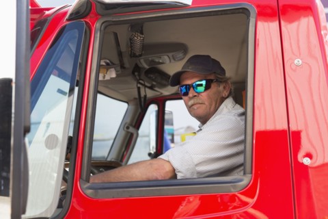 Serious Caucasian semi-truck driver wearing sunglasses