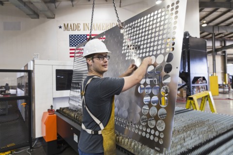 Caucasian worker fabricating metal in factory