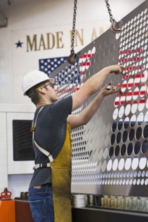 Caucasian worker fabricating metal in factory