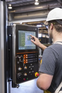 Caucasian worker using control panel in factory