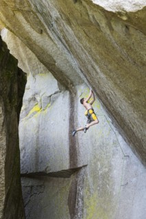 Mixed race boy hanging from rock