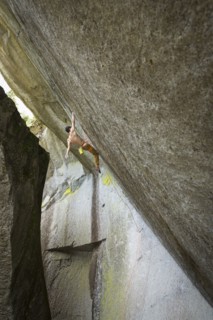 Mixed race boy hanging from rock