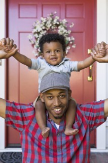 Smiling mixed race father carrying baby son on shoulders