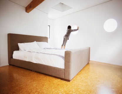 Mixed race girl looking out window in modern bedroom