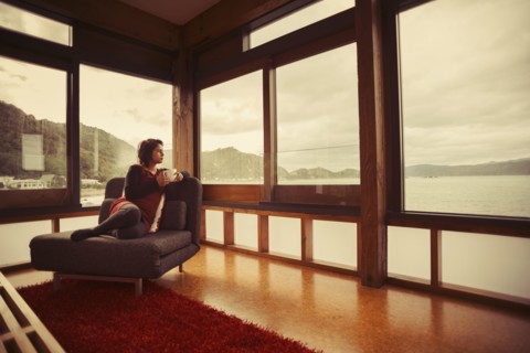 Mixed race woman looking out window of modern house