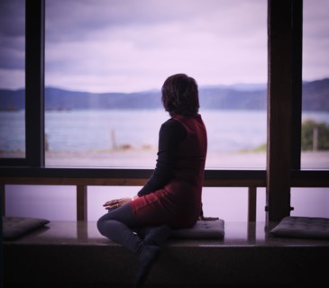 Mixed race woman looking out window of modern house