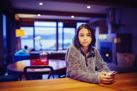 Mixed race girl using cell phone at table