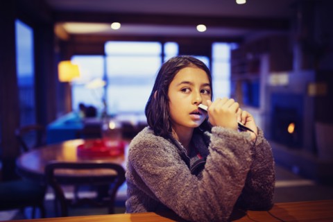Mixed race girl holding cell phone at table