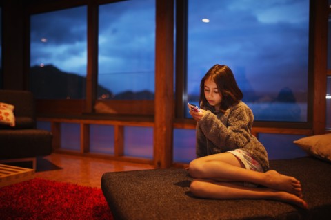 Mixed race girl using cell phone in living room
