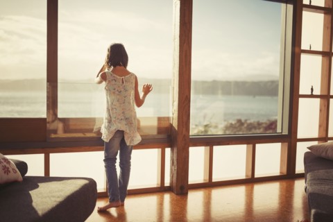 Mixed race girl looking out living room window
