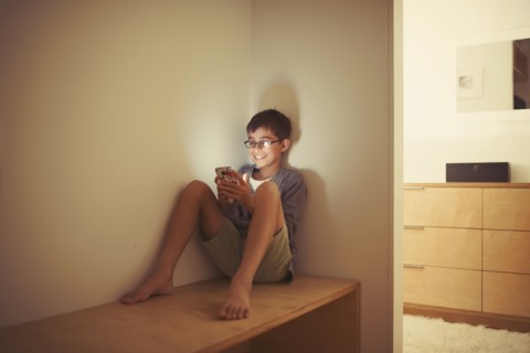 Mixed race boy using cell phone on bench