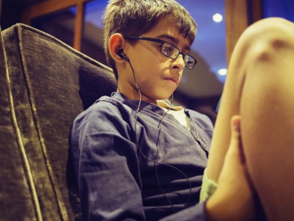 Mixed race boy listening to earbuds on sofa