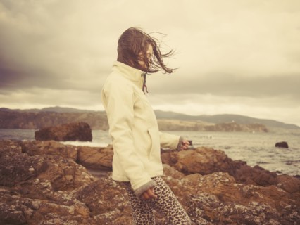 Mixed race girl walking on rocky beach