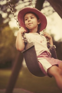 Mixed race girl playing on swing on playground