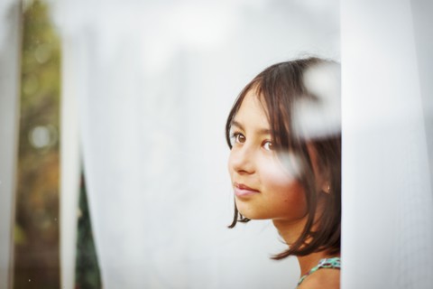 Mixed race girl standing near window
