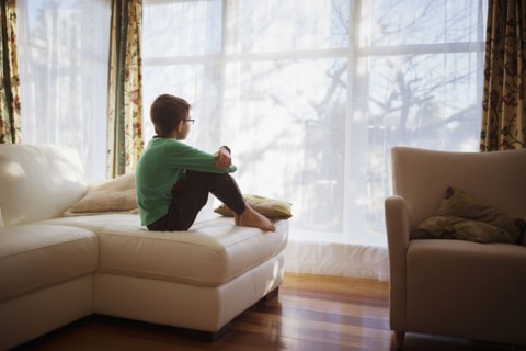 Mixed race girl looking out living room window