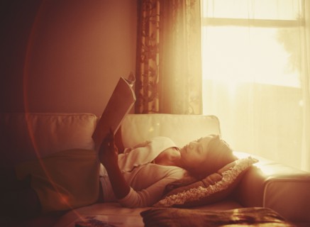 Mixed race woman using digital tablet on living room sofa