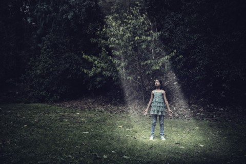Mixed race girl standing in beam of light outdoors