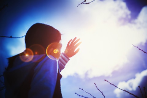 Mixed race girl shielding herself from sun lens flare