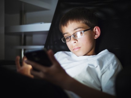 Mixed race boy texting on cell phone at night
