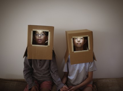 Mixed race brother and sister wearing cardboard box astronaut helmets