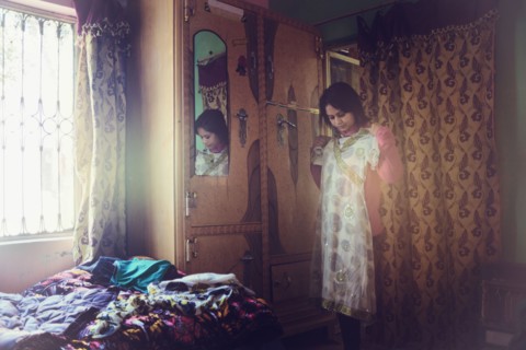 Mixed race woman examining dress in bedroom
