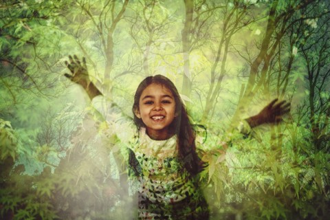 Mixed race girl standing in forest projection