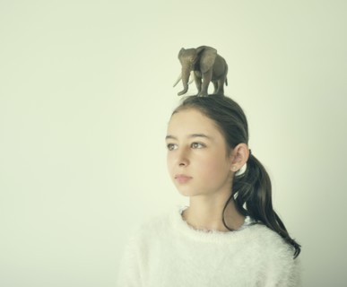 Mixed race girl holding toy elephant on head