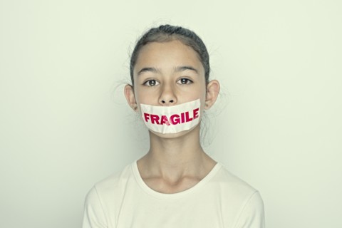 Mixed race girl wearing fragile sticker over mouth