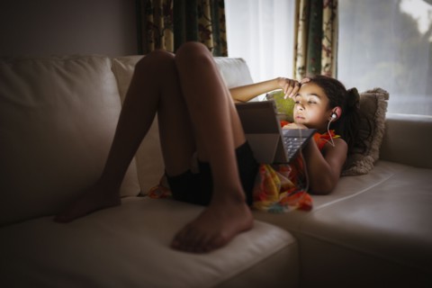 Mixed race girl using digital tablet on sofa