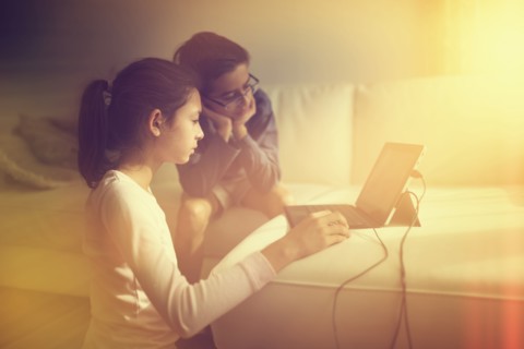 Mixed race children using laptop on sofa